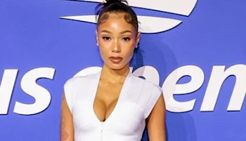 A woman with her hair in a bun wears a white, sleeveless, zippered top, standing in front of a blue background with white text.