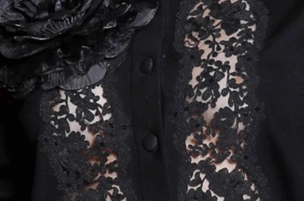 GabbrietteH&MElieSaabParisPic2 Close-up of a black button-down garment featuring sheer lace panels and a large fabric flower accent.
