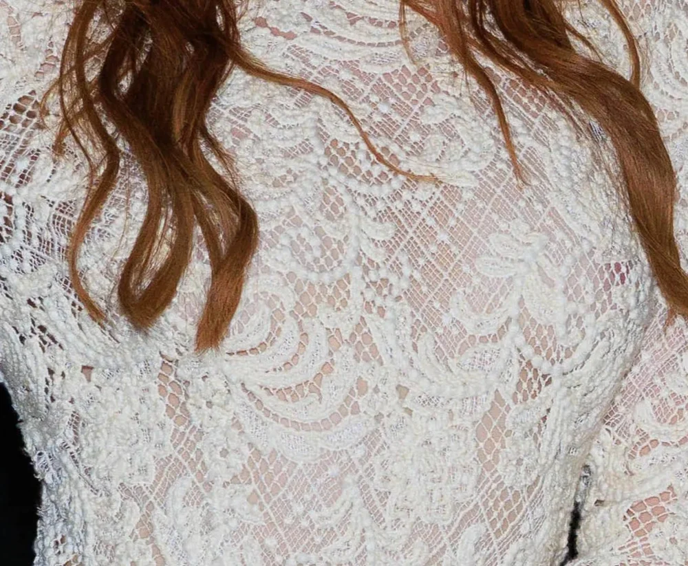 MadelainePetschNipsRunway26VogueWorldPic2 Close-up of a white lace garment worn by a person with auburn hair.