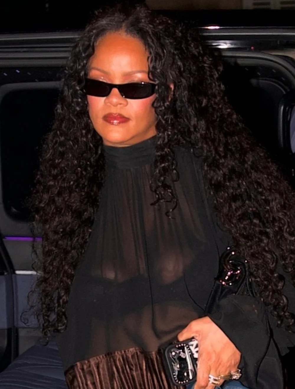 RihannaCesarRestParisPic2 Rihanna wearing black sunglasses and a sheer black top.
