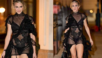 A woman wearing a sheer, black lace dress with layered fringe detailing.
