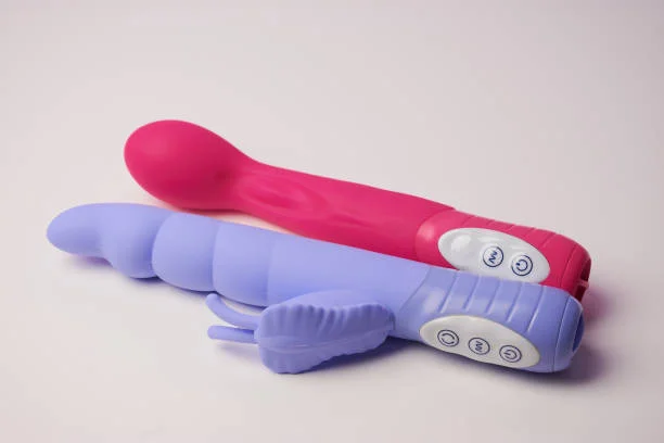 A pink wand vibrator and a purple rabbit-style vibrator with control buttons on the handles.