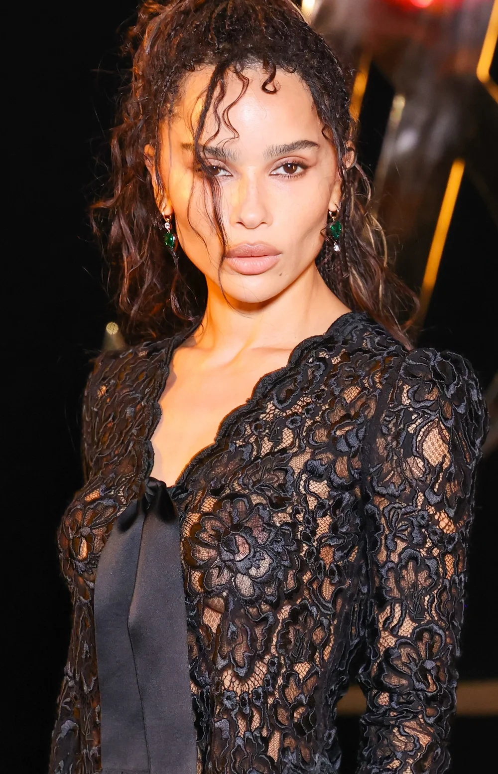 ZoeKravitzSeeThroughSLShow26PFWPic1 Zoë Kravitz wearing a black lace long-sleeved top with a black ribbon tie at the neckline.